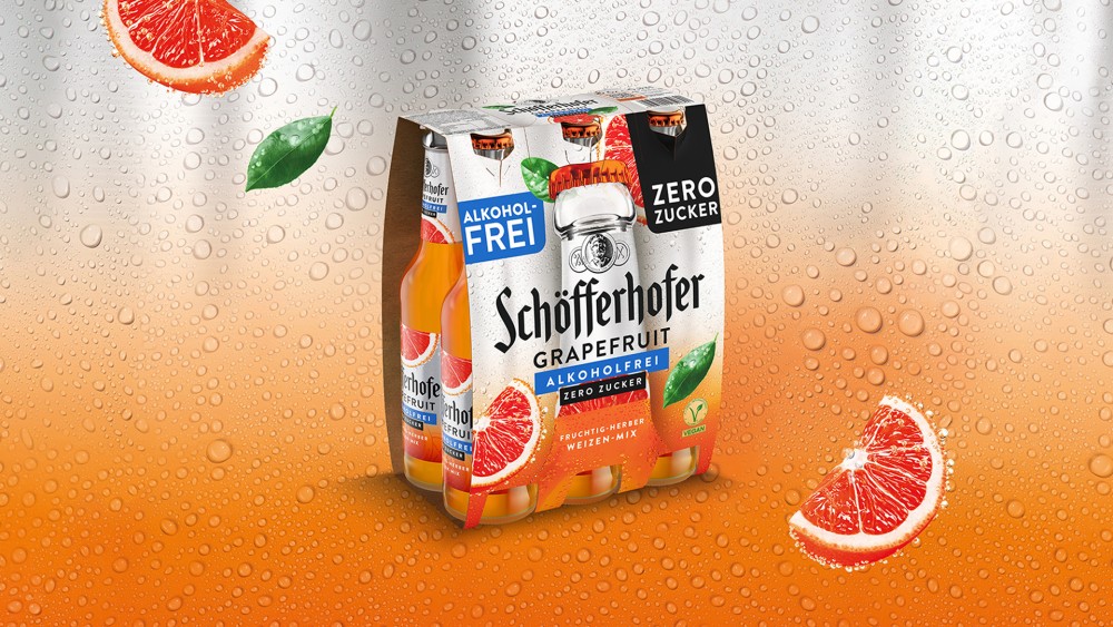 Ein Schöfferhofer Grapefruit Alkoholfrei Zero Sixpack vor betautem orange silbernem Hintergrund.